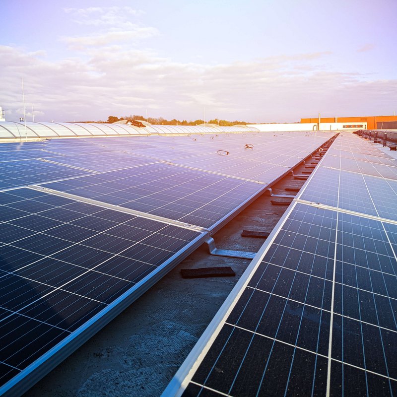 Viele Solaranlagen (Photovoltaik) Panele mit Sonnenschein auf dem Firmendach von Lebosol und Semfill