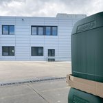 Graues Gebäude mit 2 Etagen und Fenstern. Grüne Lebosol Kanister am Rand des Bildes zu sehen.