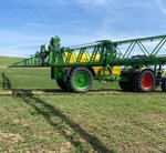 Traktor mit Spritzarmen der über ein Getreidefeld fährt