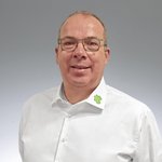 Mann mit wei&szlig;em Hemd und Lebosol-Bl&auml;ttchen am Kragen vor grau-wei&szlig;er Wand