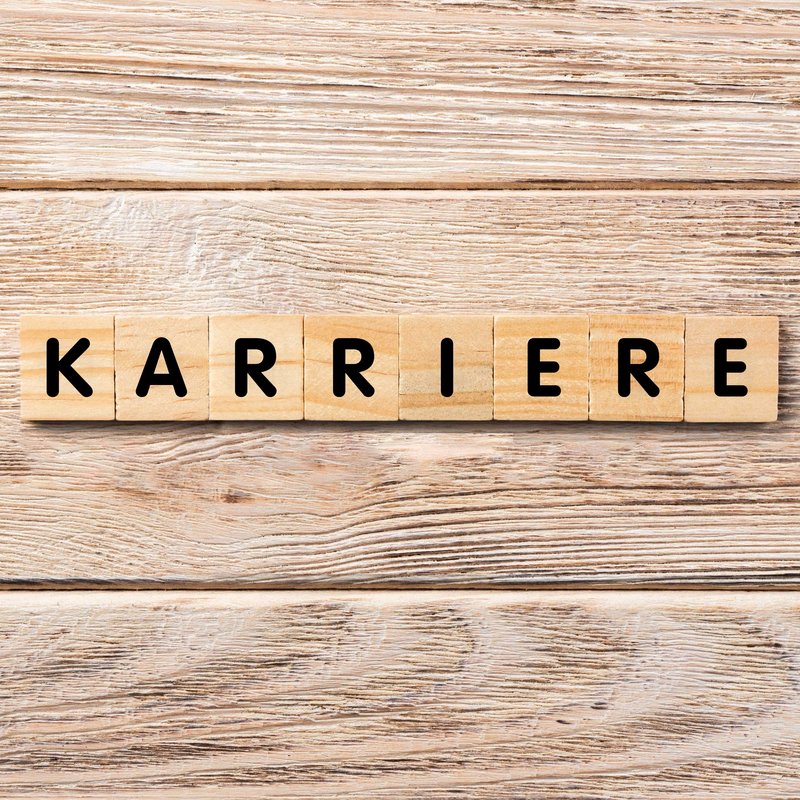 Holzhintergrund mit Würfel auf denen Buchstaben stehen welche das Wort Karriere ergeben