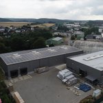 Luftaufnahme von drei Gebaeuden mit Solaranlagen.