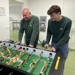 Drei Personen in grünem Lebosol® Pullover spielen an einem Tischkicker