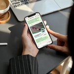 Person am Schreibtisch mit Handy in der Handy und geöffnetem Lebosol® WhatsApp Kanal