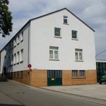 Weißes Gebäude im beigem Untergeschoss. Familienhausähnlich.