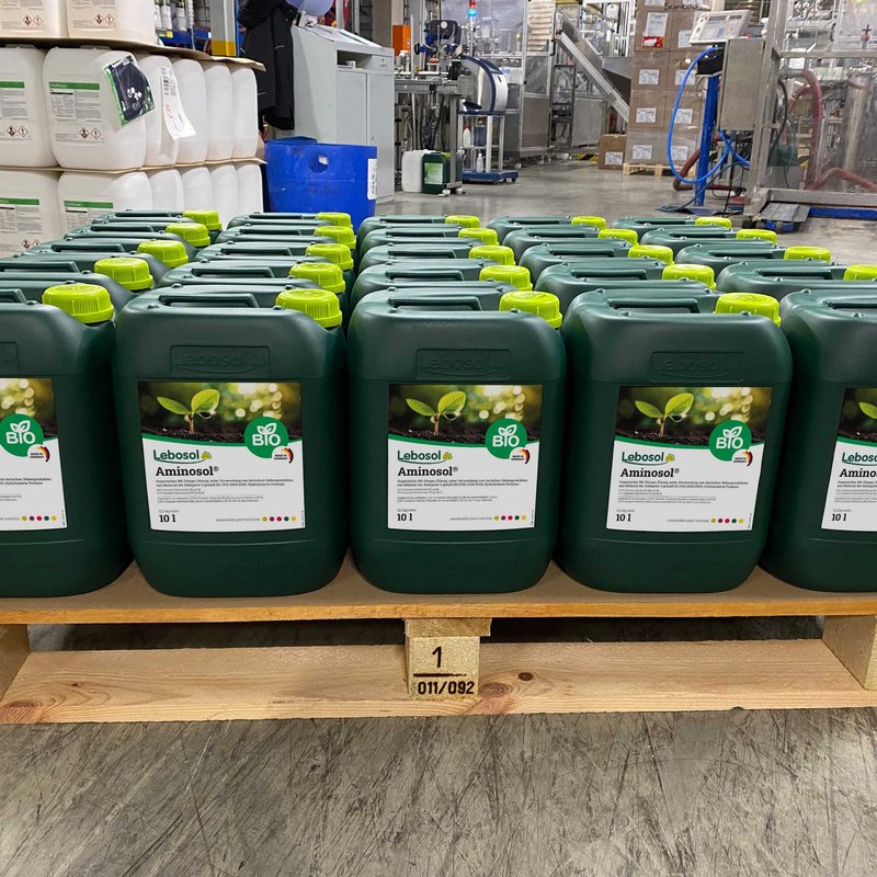 Eine Reihe von 10 Liter dunkelgrünen Kanistern Aminosol® auf einer Holzpalette
