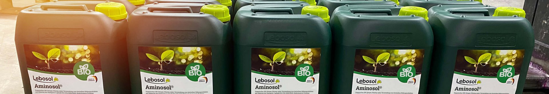 Eine Reihe von 10 Liter dunkelgrünen Kanistern Aminosol® auf einer Holzpalette