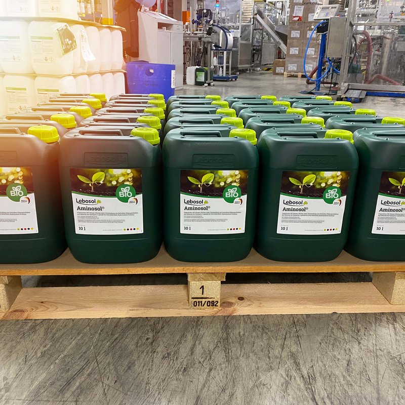 Eine Reihe von 10 Liter dunkelgrünen Kanistern Aminosol® auf einer Holzpalette