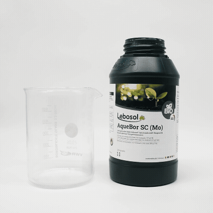 Wei&szlig;e Fl&uuml;ssigkeit wird aus Gr&uuml;ne Flasche in Becherglas gesch&uuml;ttet.